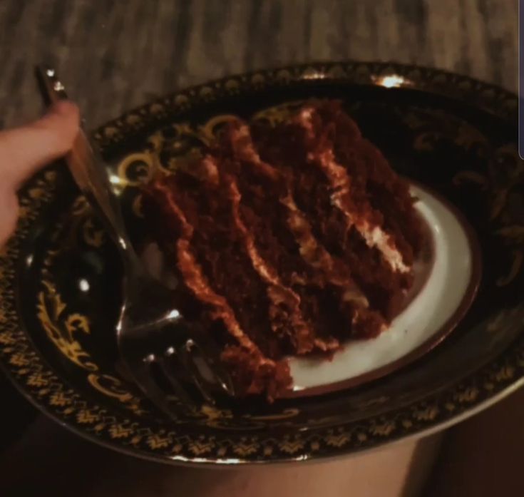 someone holding a plate with a piece of cake on it