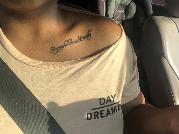 a woman with a tattoo on her chest sitting in a car