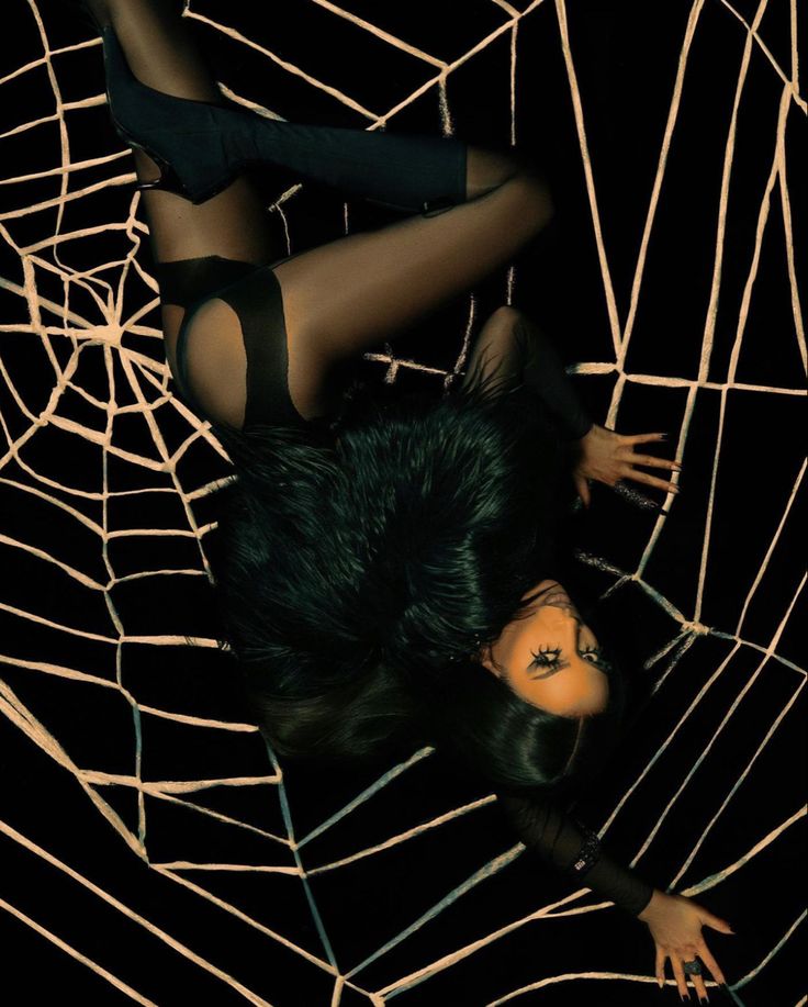 a woman laying in a spider web with her legs spread out and hands on her hips