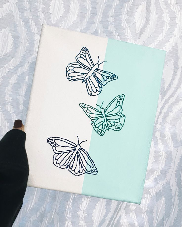 a person holding up a piece of paper with two butterflies on it and one is blue