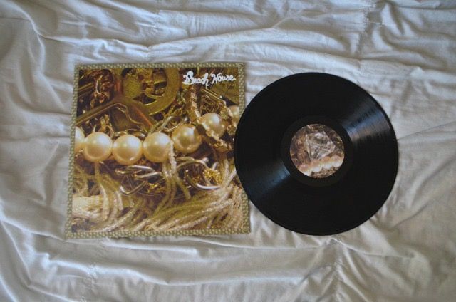 a record sitting on top of a bed next to a white sheet with an album cover