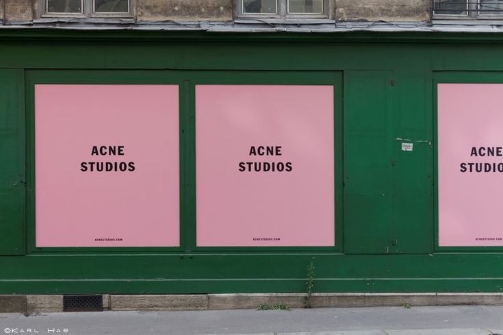 three pink posters on the side of a building with acne studios written on them