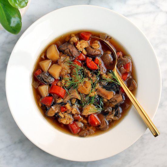 a white bowl filled with stew next to a green leafy plant on a table