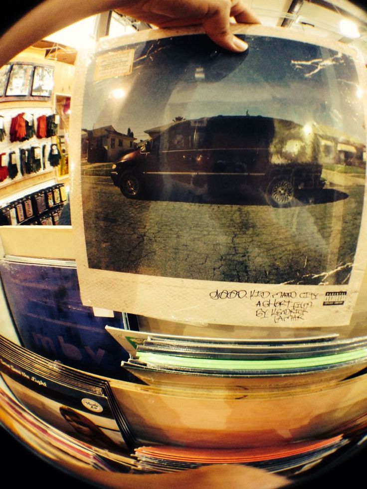 a person holding up a photo in front of a store display with cars on it