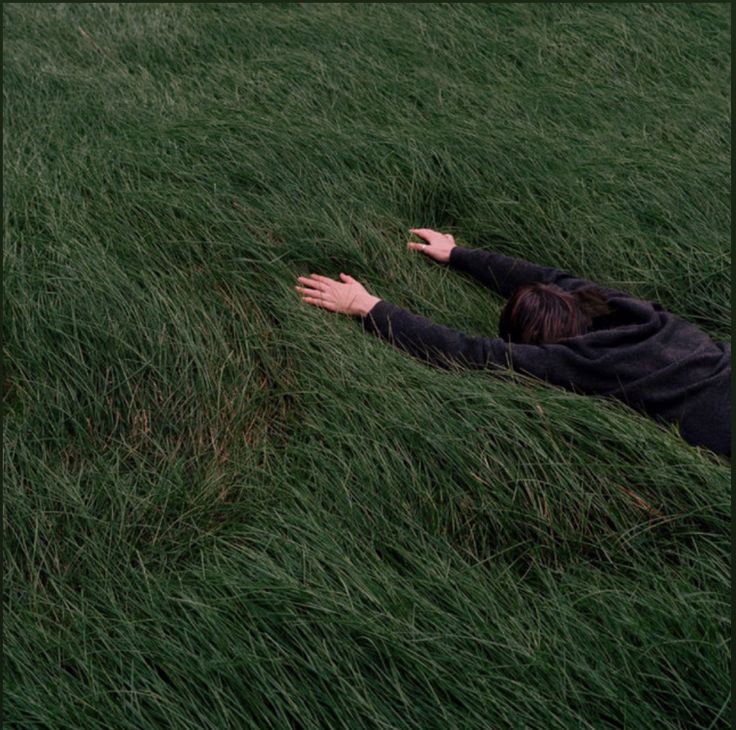 a person laying in the grass with their arms out