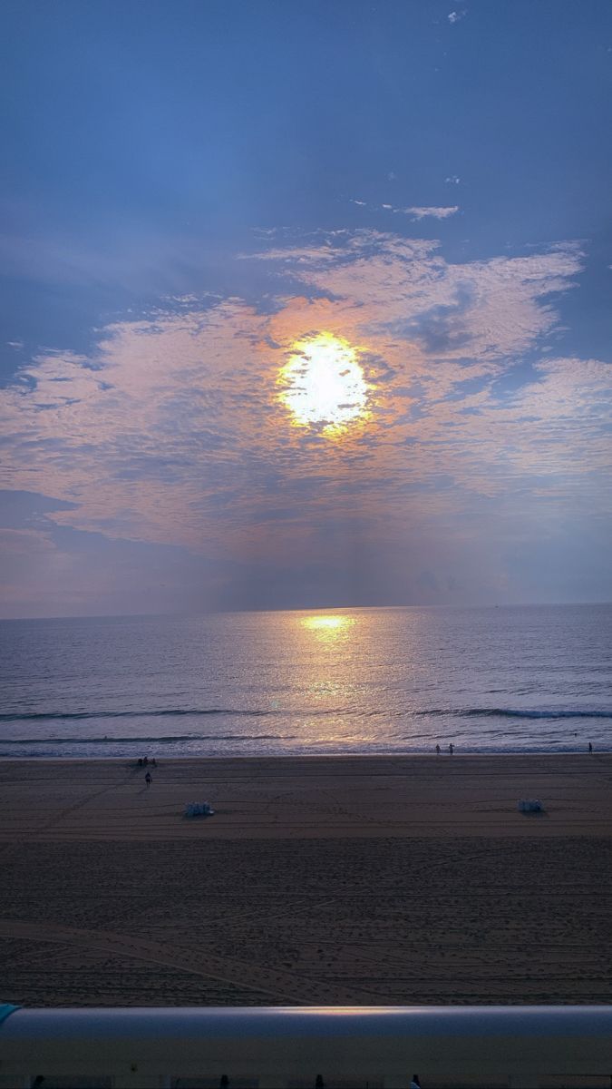 the sun is setting over the ocean and beach