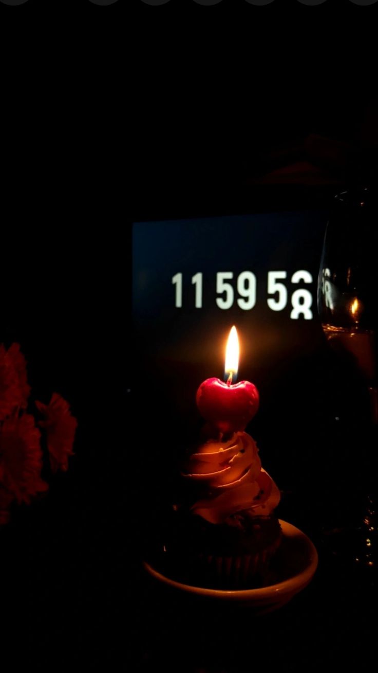 a cupcake with a lit candle sitting in front of a sign that reads 1195