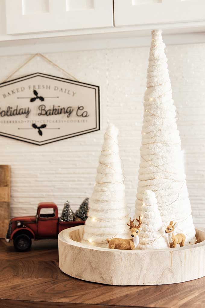 three white christmas trees sitting on top of a wooden table