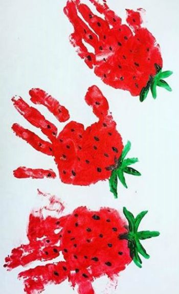 two handprints made to look like strawberries with green leaves and black dots