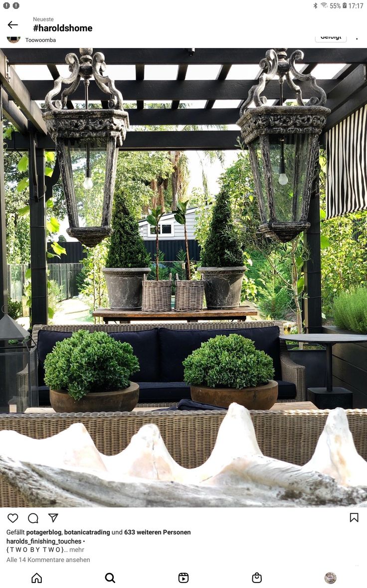 an outdoor area with potted plants and two hanging lights in the middle of it