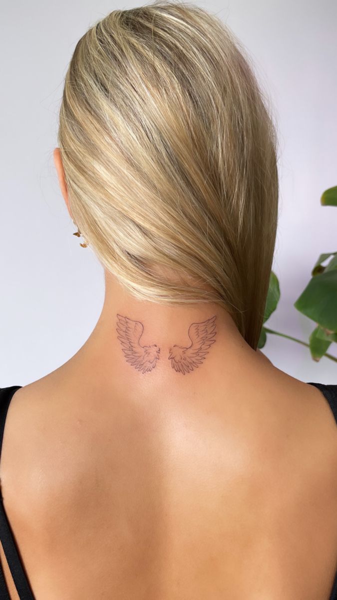 the back of a woman's neck with an angel tattoo on her left side