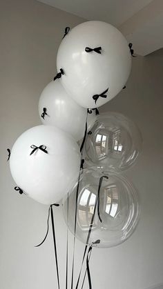 white balloons with black bows on them are in a vase next to a wall and floor