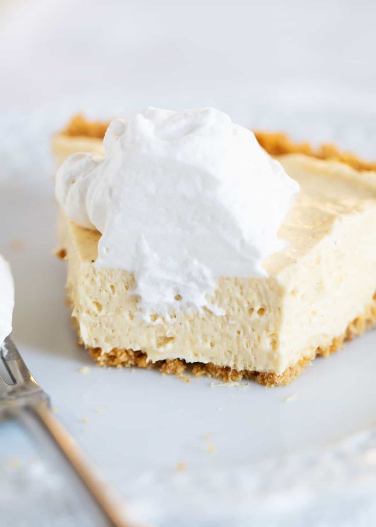 a piece of cheesecake with whipped cream on top is sitting on a white plate