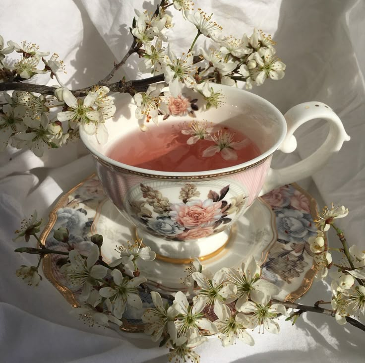 a tea cup and saucer sitting on top of a plate with flowers in it