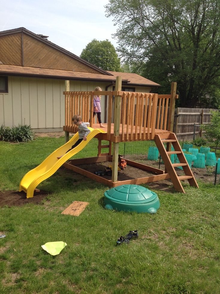 a child playing on a wooden slide in the yard