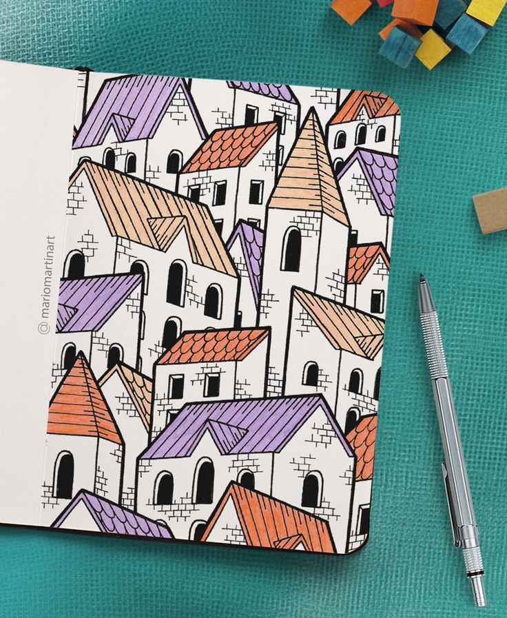 an open notebook with houses drawn on it next to crayons and pencils