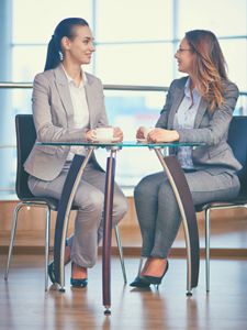 two women sitting at a table talking to each other