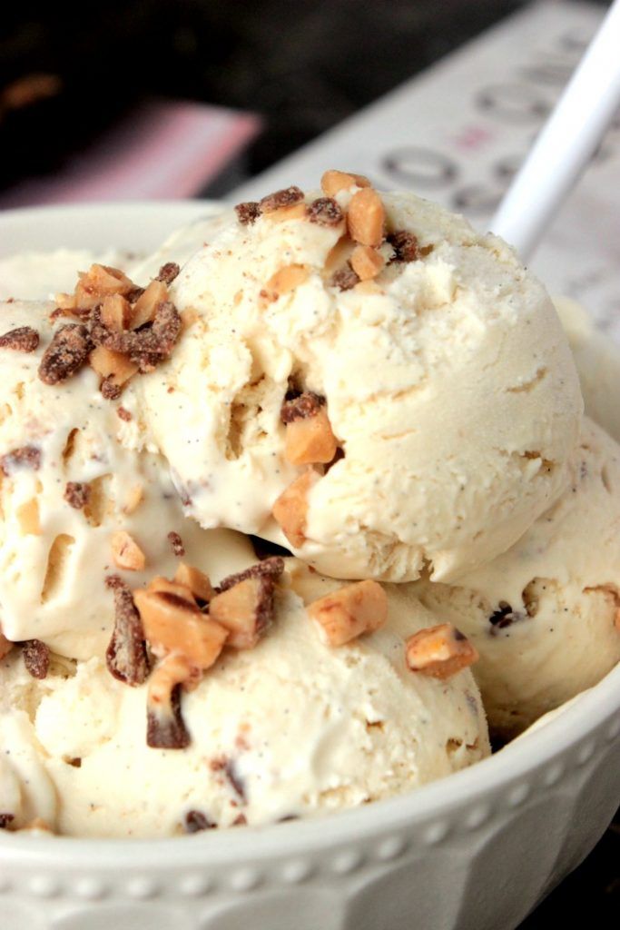 two scoops of ice cream in a white bowl with chocolate chips and nuts on top