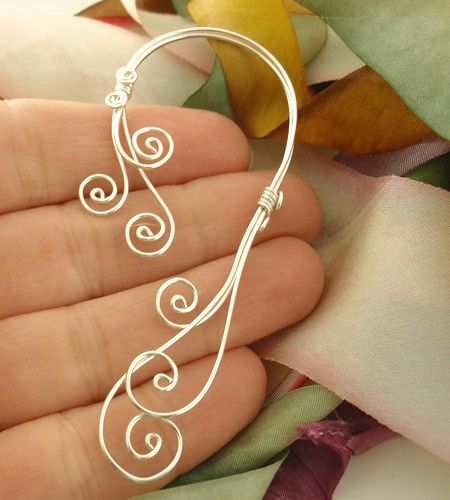 a hand holding a silver wire with swirls on it