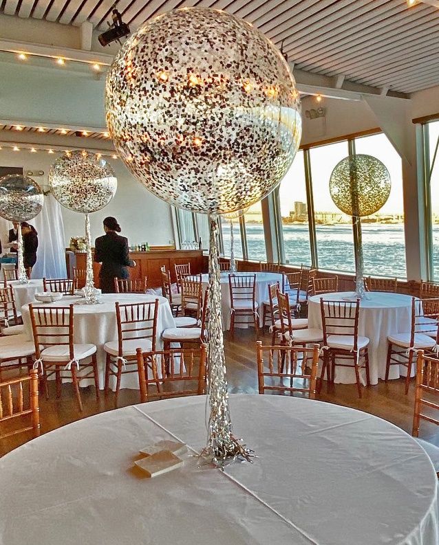 a room filled with lots of tables covered in white tablecloths and round centerpieces