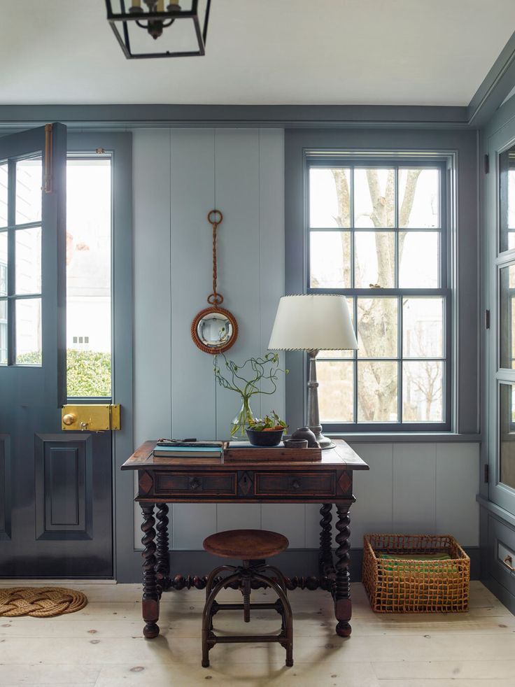 a room with blue walls and wooden floors has a lamp on the table next to it