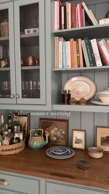 a kitchen with blue cabinets and bookshelves filled with bottles, plates and other items