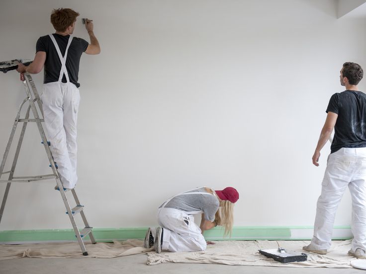 two men are painting the walls in an empty room