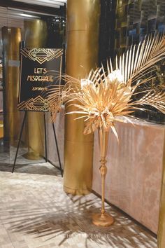 a tall gold vase sitting on top of a wooden floor next to a golden pole