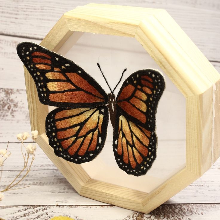 an orange butterfly sitting on top of a wooden frame