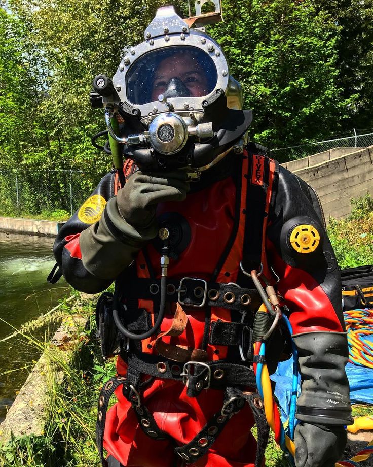 a man wearing a diving suit while standing next to a river