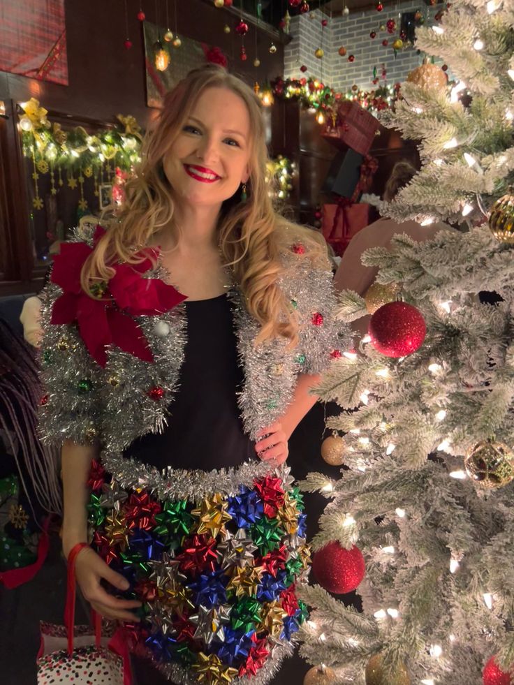 a woman standing next to a christmas tree