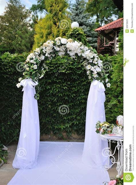 a wedding arch decorated with white flowers and greenery