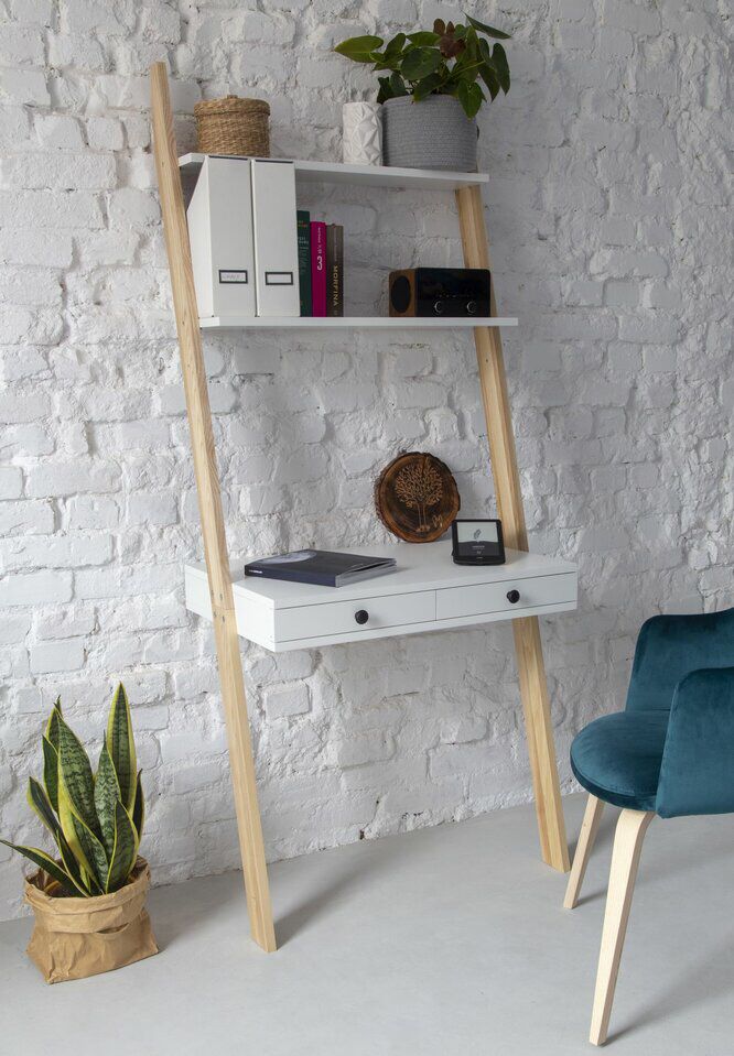 a white desk and chair in front of a brick wall with bookshelves on it