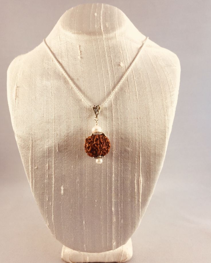 The elegant Shivam Rudraksha Pendant is an expression of the pure Divine nature of the Himalayan Rudraksha, which are the seed of a broad-leafed evergreen tree found mainly in the Himalayan foothills. It is believed that wearing these beads bring clarity, and create positive energy for the body, mind and soul. They are the eternal symbol of a Himalayan Yogi and coveted by Shiva Himself (Spirit). This pendant is accented with fresh water Pearls and Sterling Silver (925) findings. Each one comes w Spiritual Silver Beaded Necklaces For Puja, Spiritual Necklaces With Silver Beads For Puja, Natural Spiritual Jewelry As A Gift, Traditional White Jewelry For Healing, Traditional White Healing Jewelry, Spiritual Silver Beads Mala Gift, Spiritual Natural Jewelry For Meditation, Natural Spiritual Jewelry For Meditation, Traditional Necklace As A Gift