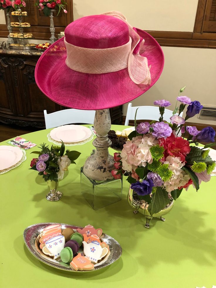 a pink hat sitting on top of a table next to plates and cups filled with food