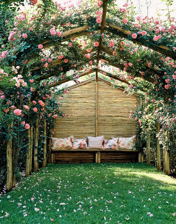 a wooden bench sitting in the middle of a lush green field with roses growing on it