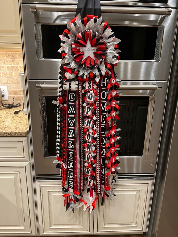 a red, white and silver christmas decoration hanging from the side of an oven door