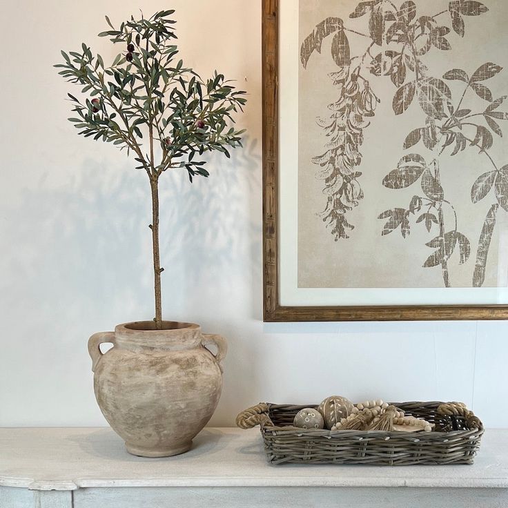 a potted plant sitting on top of a table next to a basket filled with rocks