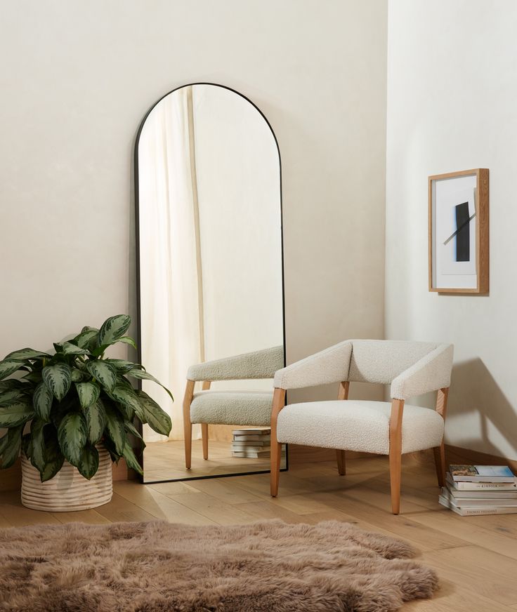 a living room with a chair, mirror and potted plant on the floor in front of it