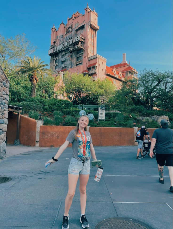 a woman standing in front of a castle with her arms out and one hand on her hip