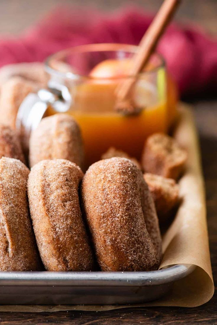 some sugared donuts are on a plate with orange juice