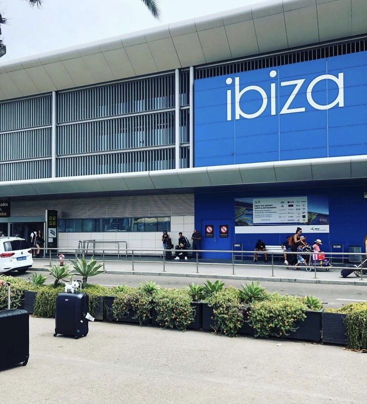 an airport with people and luggage in front of the building that has ibiza written on it