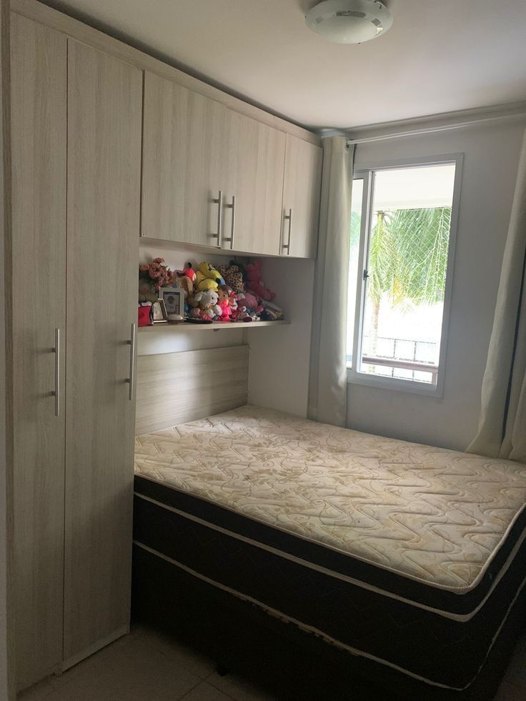 a bedroom with a bed, cupboards and window