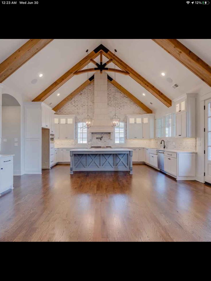 a large open kitchen with white cabinets and wood beams on the ceiling is shown in this image