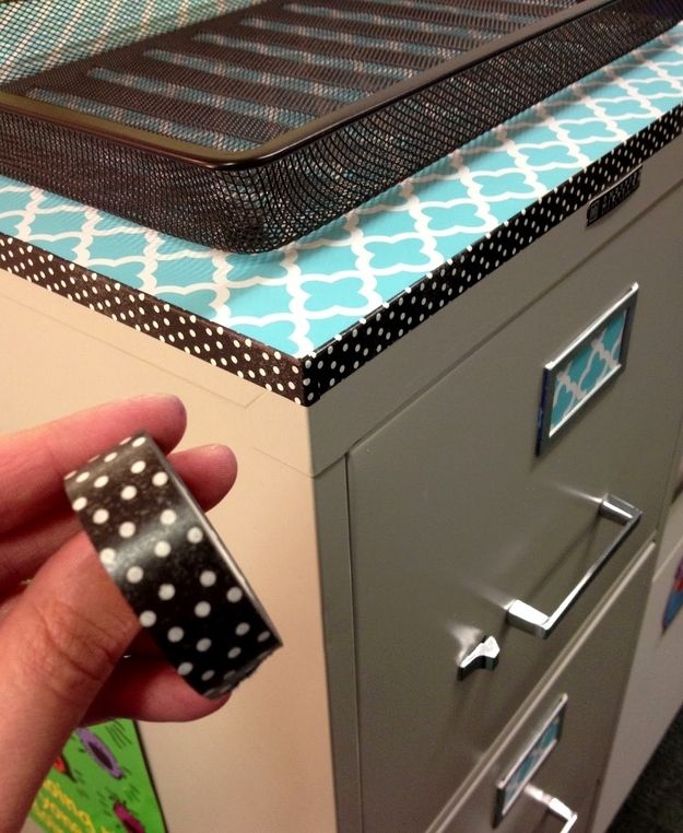 a hand holding a black and white polka dot cup in front of a filing cabinet