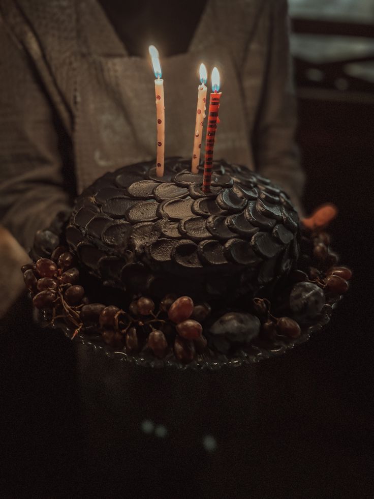 a person holding a cake with candles on it