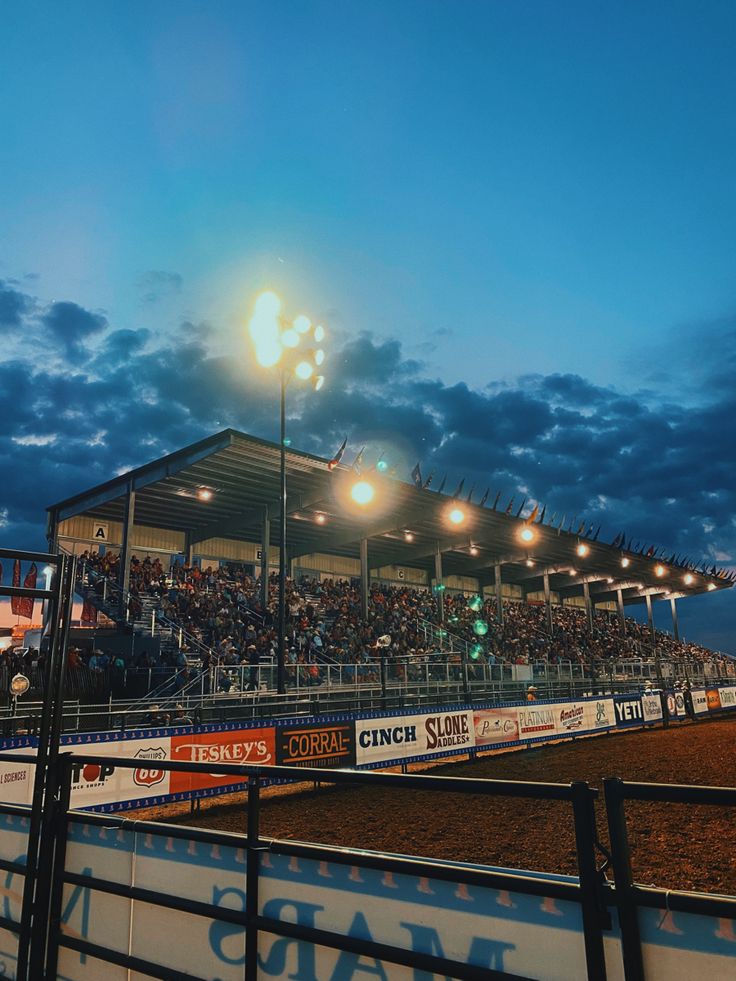 an empty stadium at night with the lights on and people in the stands looking on