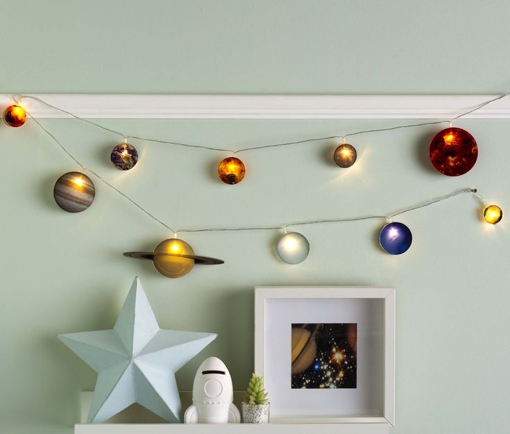 a string of solar system lights hanging from the ceiling above a shelf with an ornament on it