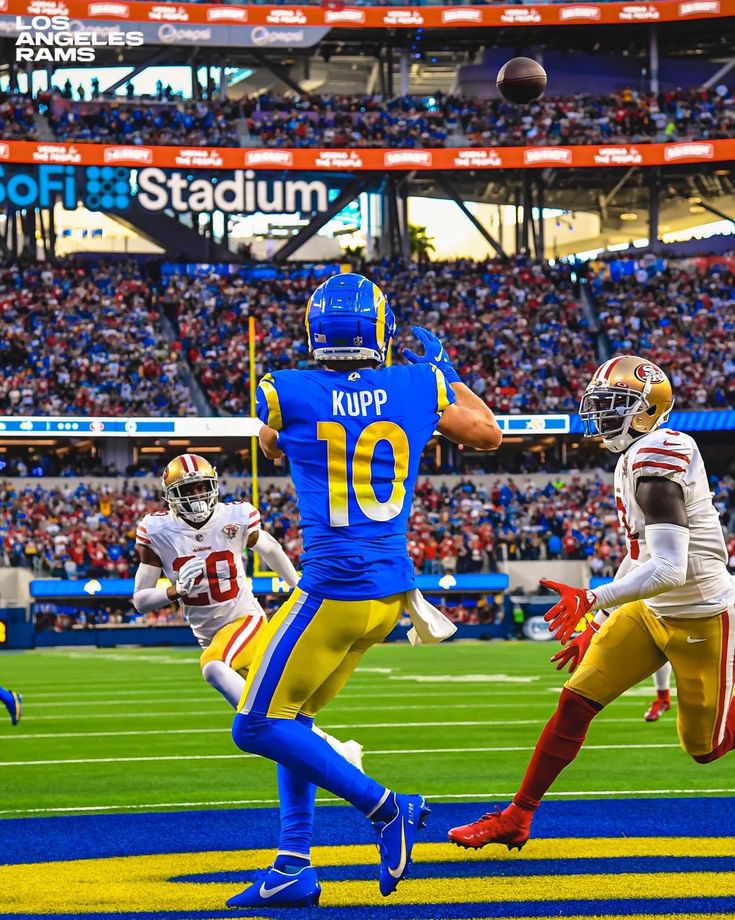 a football player running with the ball in his hand and another person jumping up to catch it