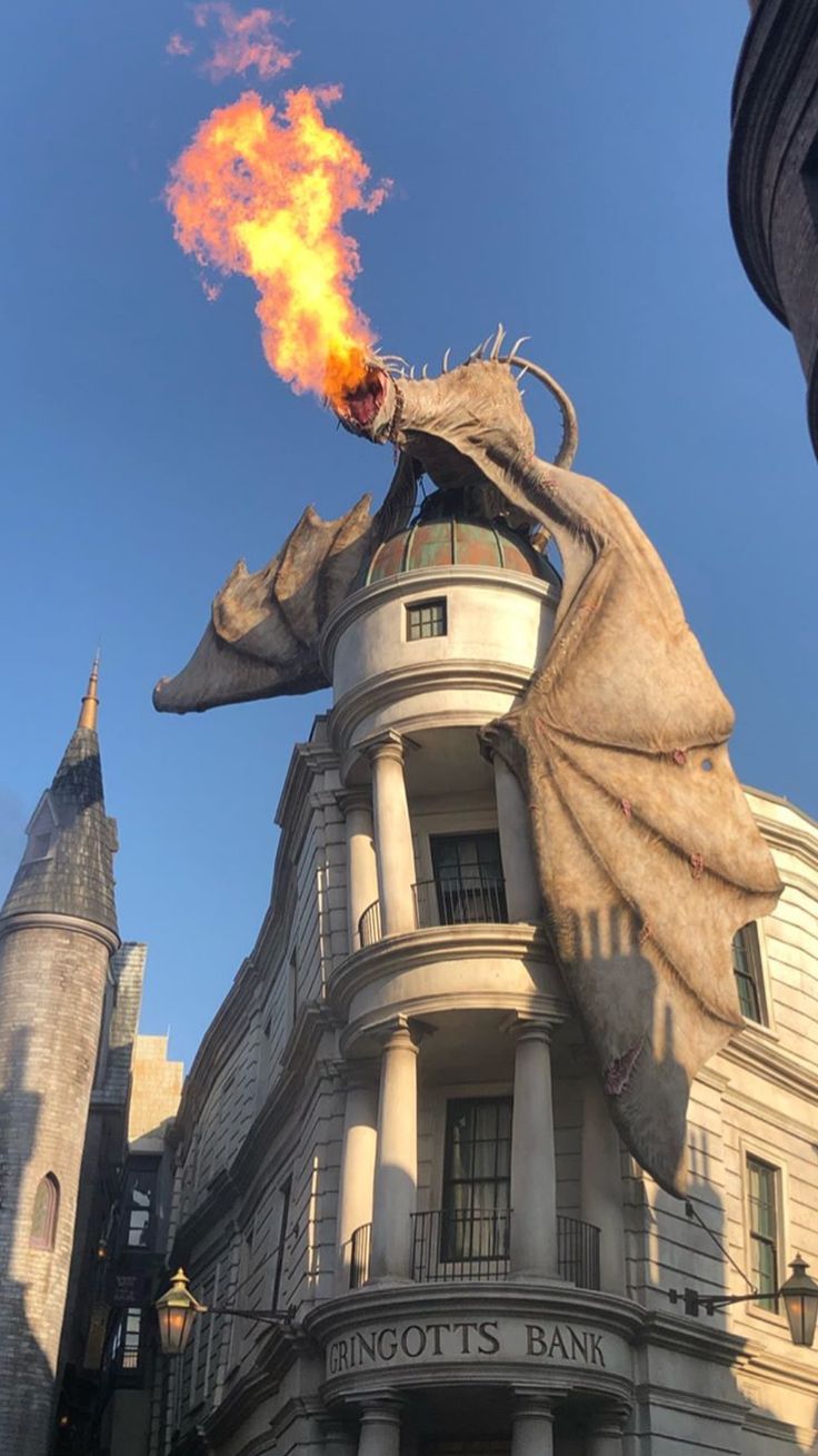 a dragon statue on top of a building with fire coming out of it's mouth